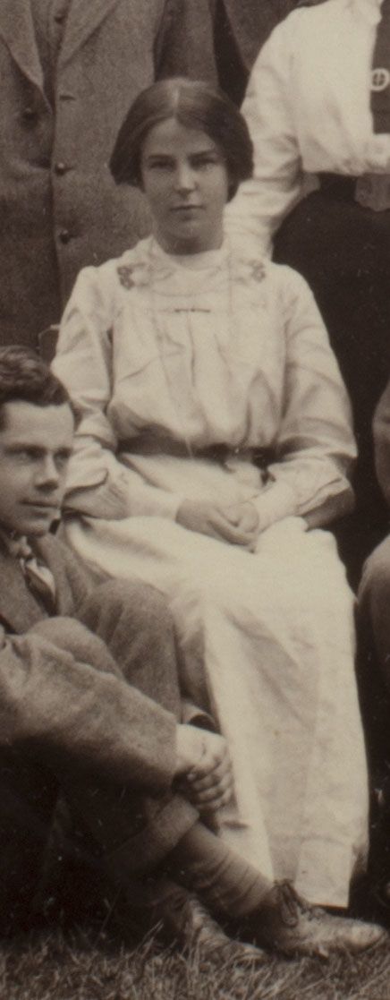 Formal photograph of woman seated outside. She has her hands in her lap.